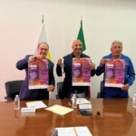 Tres funcionarios sostienen los carteles de la Carrera Atlética Teletón 2025 durante la conferencia de prensa; al centro se muestra también una medalla representativa del evento.